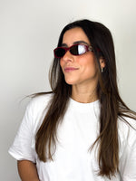 Load image into Gallery viewer, Woman wearing red sunglasses and a white t-shirt against a plain background
