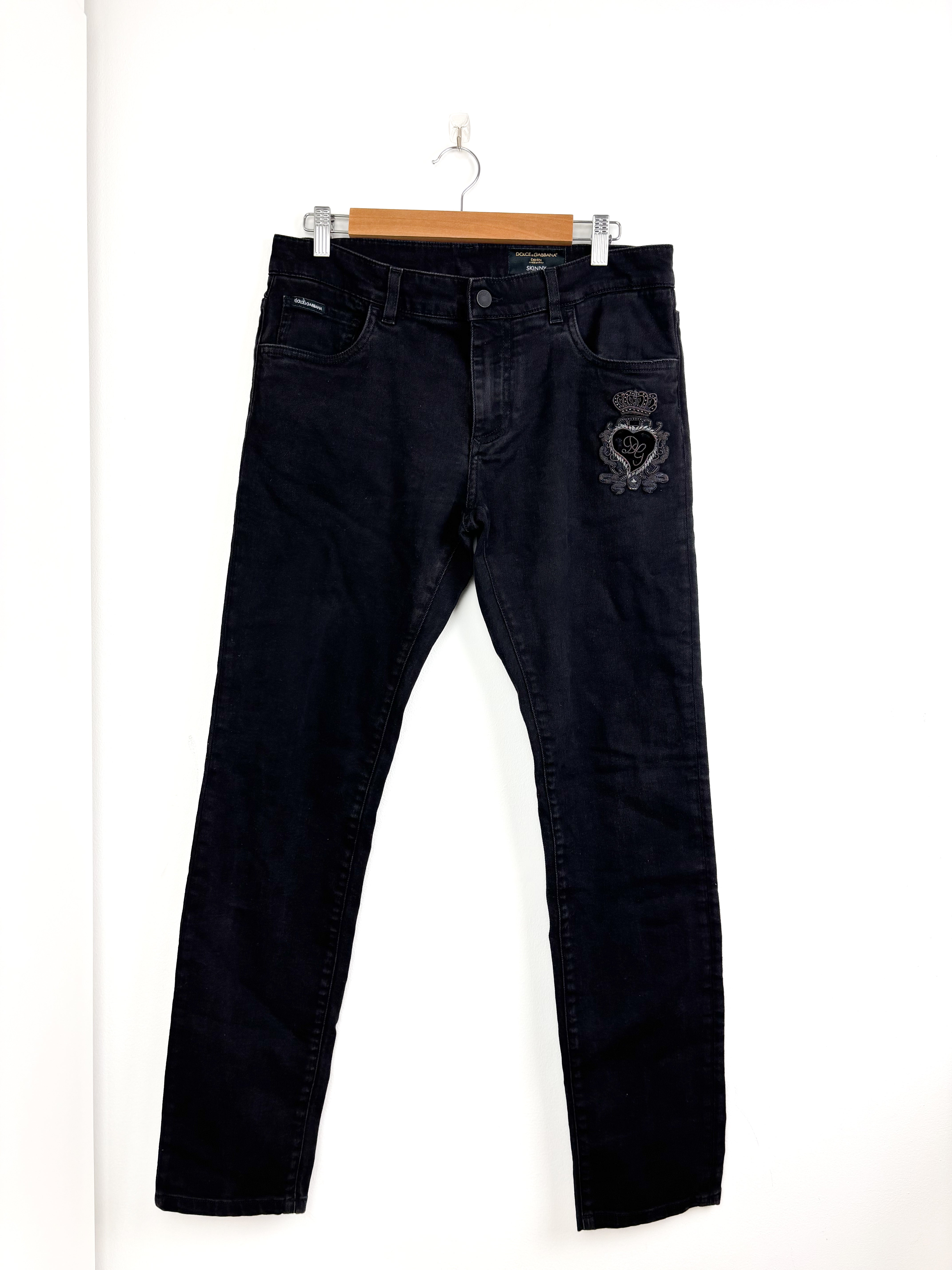 Black jeans with a heart design on a hanger against a white background